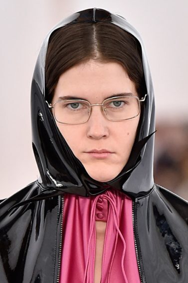 Modelo usa capuz preto sobre roupa rosa