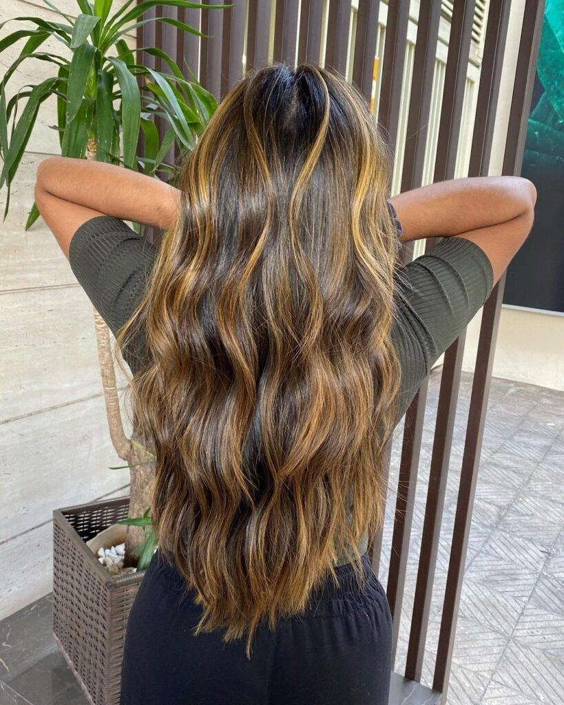 mulher de costas mostra cabelo morena iluminada mel longo ondulado
