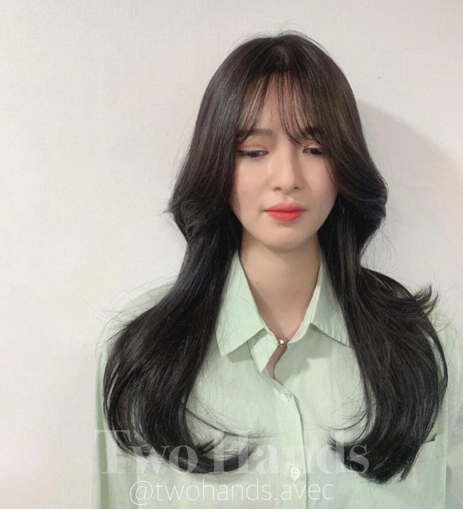 Mulher asiática com camisa verde clara e mullet feminino longo no cabelo preto liso estilo octopus hair ou polvo