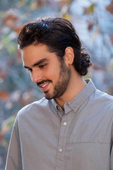 Homem usa cabelo penteado para trás com gel, ou seja, slicked back hair para cabelo cacheado