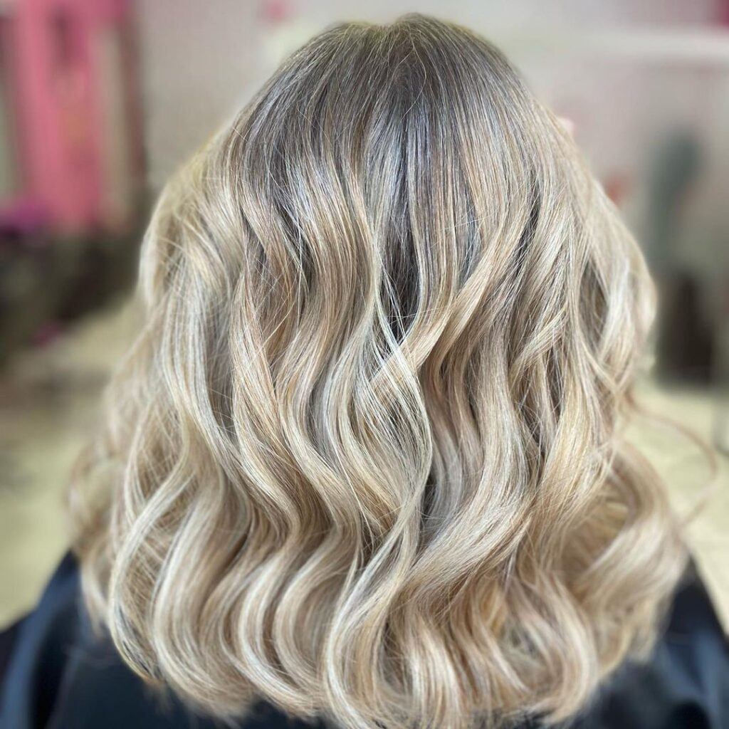 Mulher posa de costas com foco no cabelo long bob com balaiagem perolada