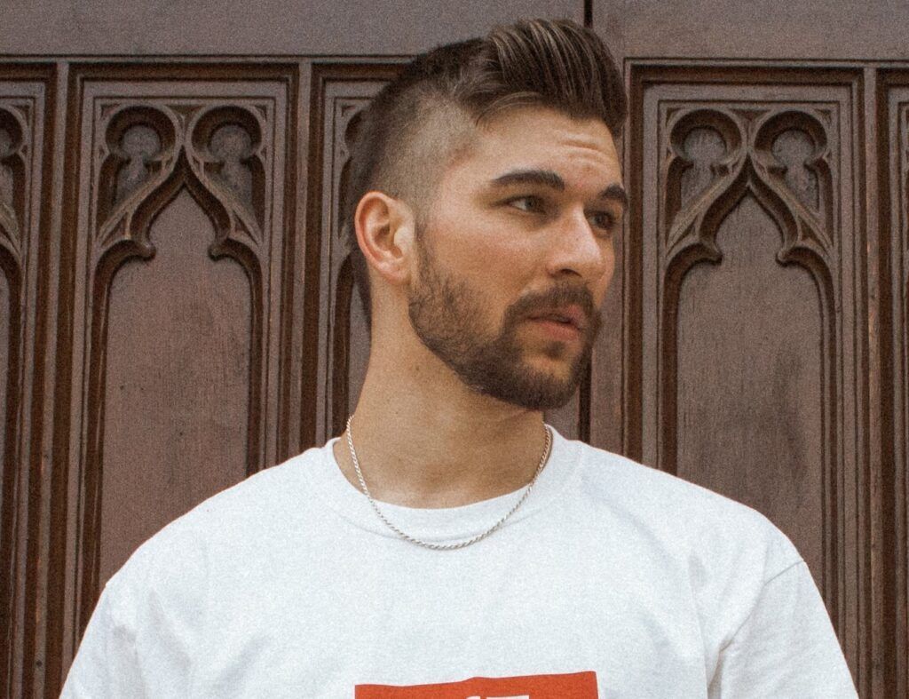 Homem posa de camiseta branca e cabelo curto estilo skatista