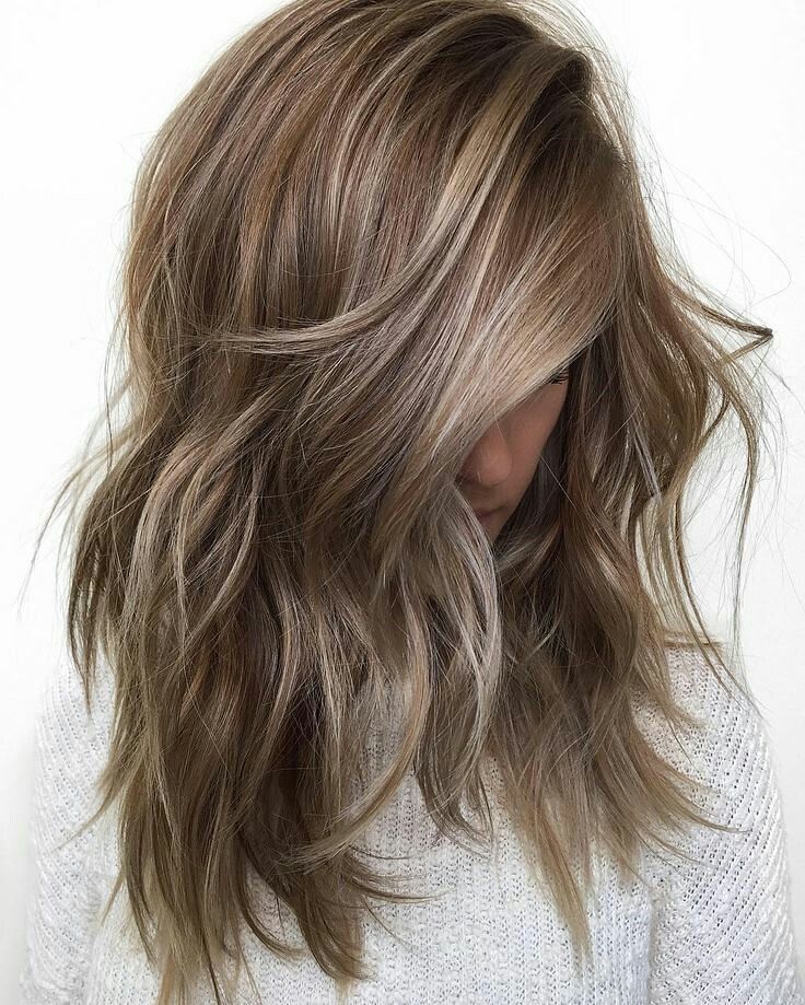Modelo com cabelo loiro escuro acinzentado jogado na frente do rosto