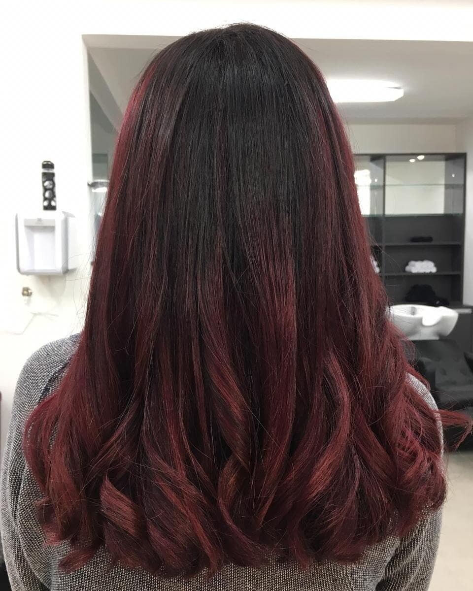 mulher de costas destacando o cabelo longo preto com mechas vermelhas