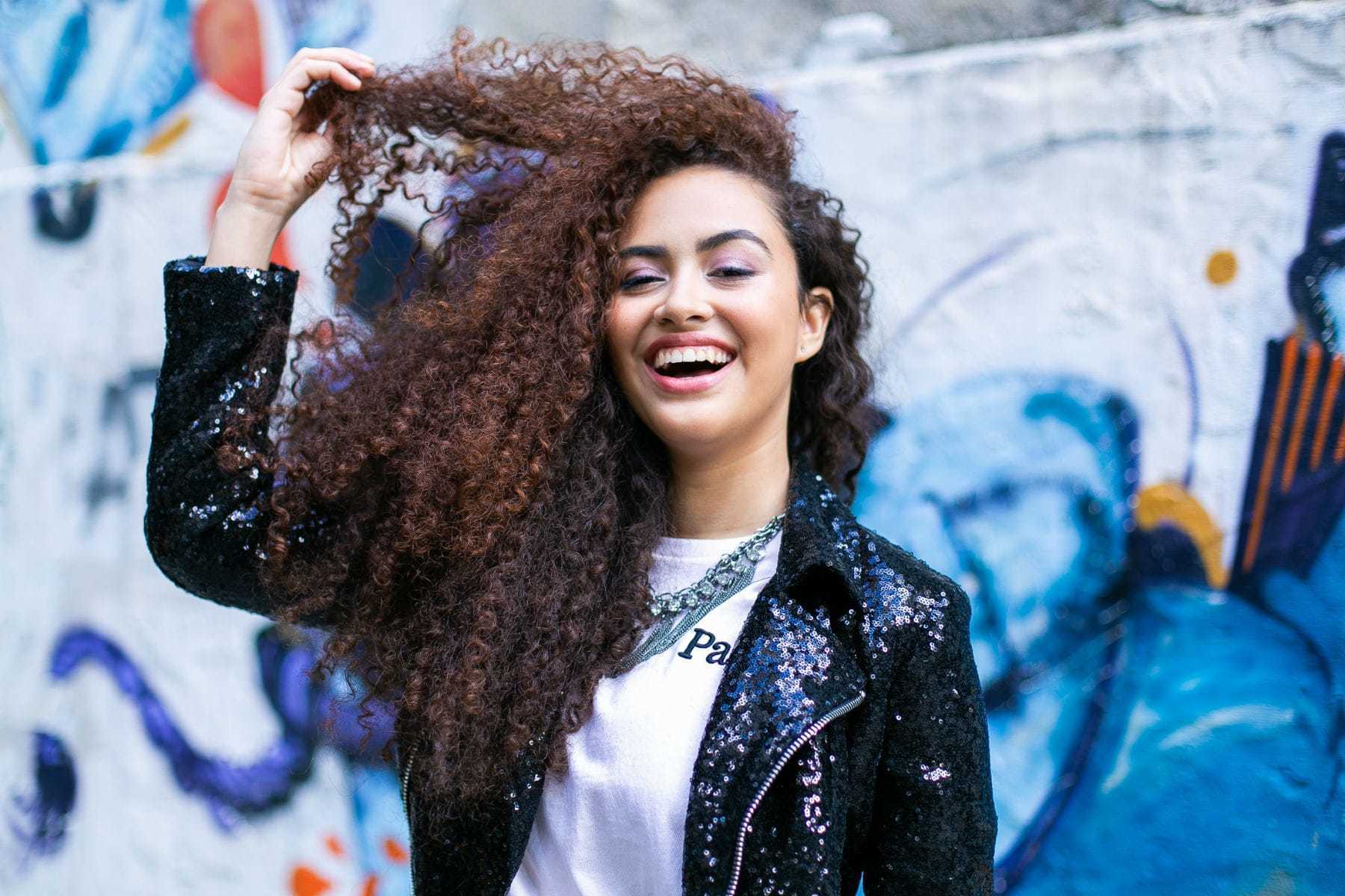Modelo com cabelo cacheado longo jogado para o lado