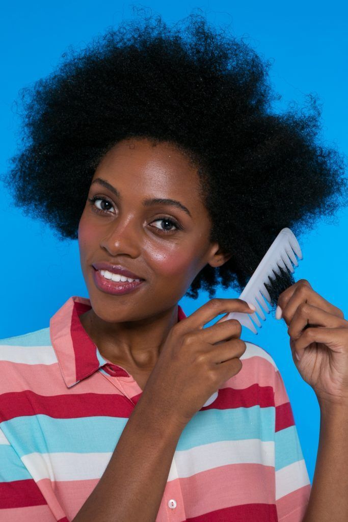 modelo de cabelo crespo penteando o com pente de dente largo