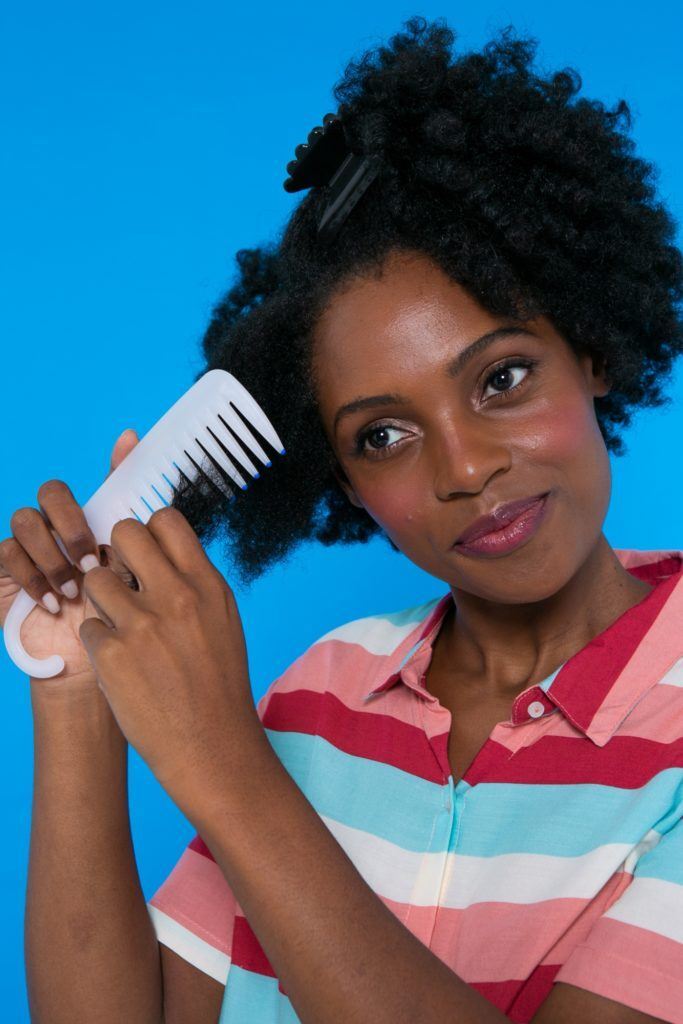 modelo de cabelo crespo penteando o cabelo afro com pente largo