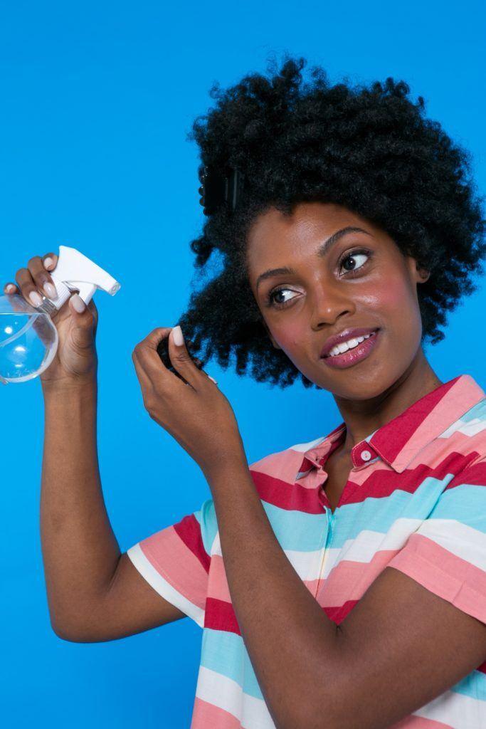 modelo de cabelo afro borrifando os fios para pentear cabelo crespo
