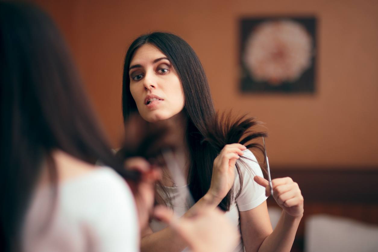 mulher de cabelo castanho longo cortando cabelo sozinha