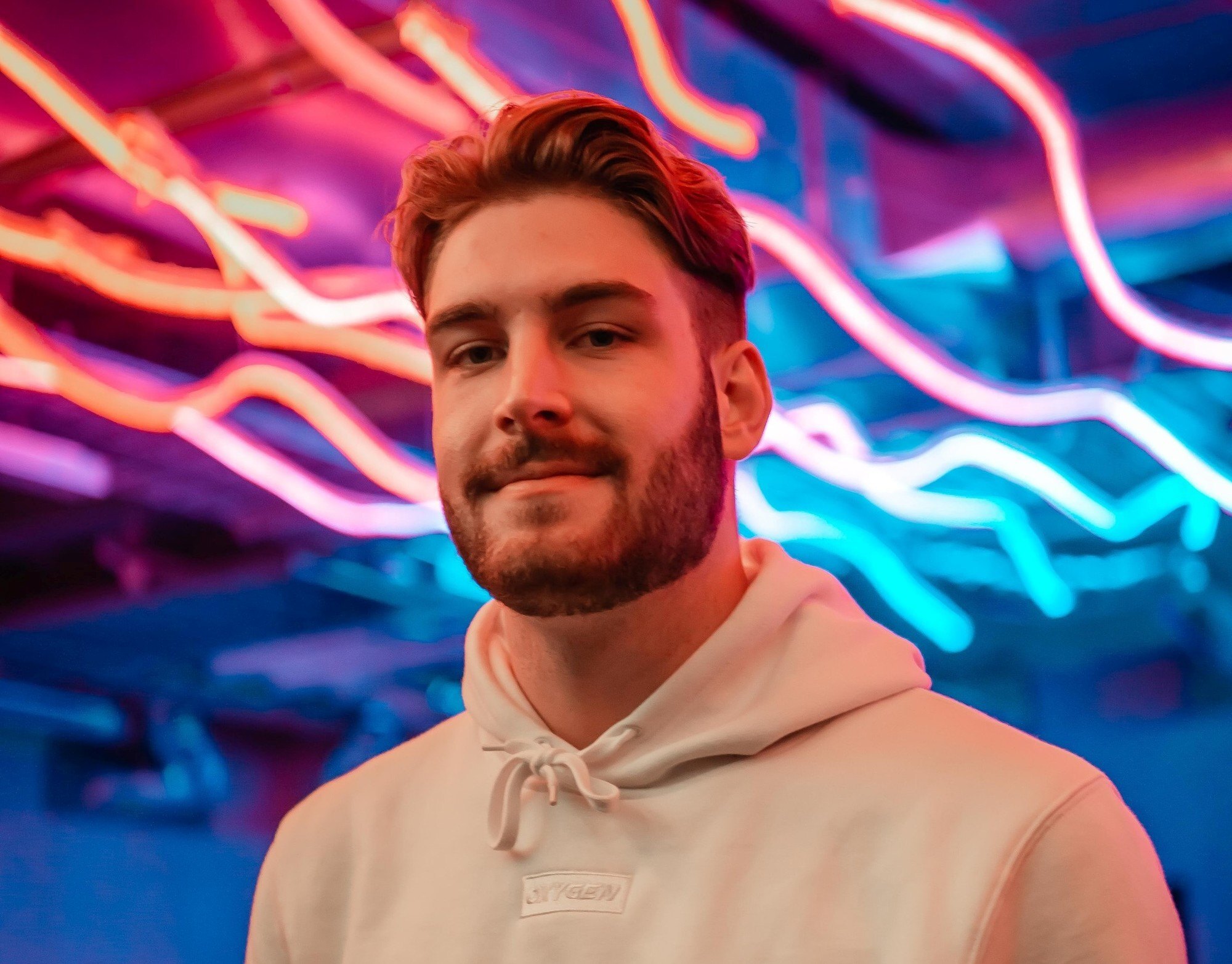 homem posa de moletom claro em fundo colorido com cabelo undercut com topete