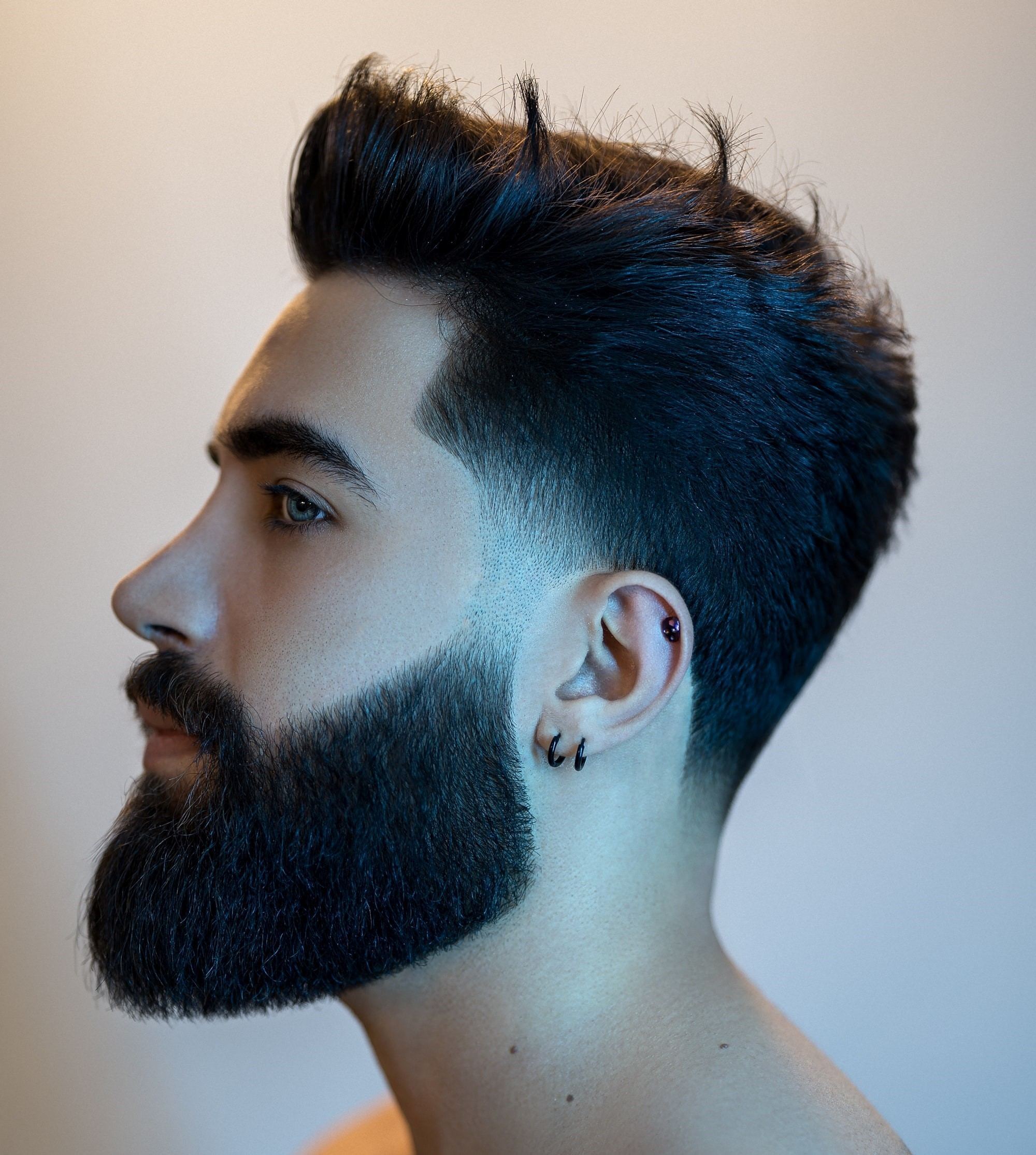 Homem de barba e corte undercut degradê posa de perfil