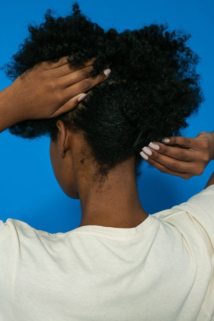 Cabelo crespo sendo repartido para preparação do penteado