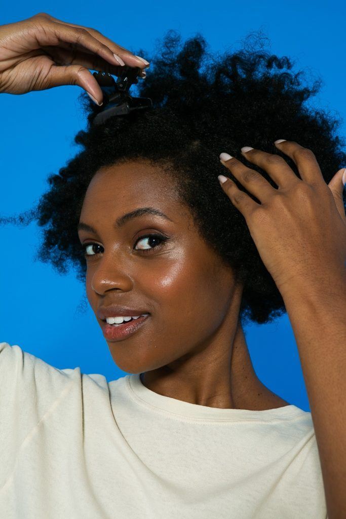 Cabelo crespo sendo repartido para preparação do penteado