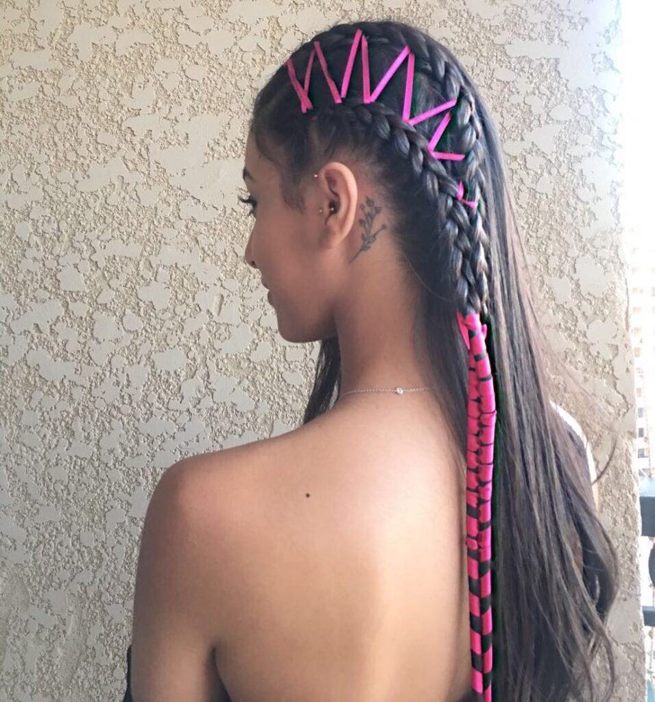 Mulher de cabelo castanho de trança com fita de cetim cor de rosa no cabelo