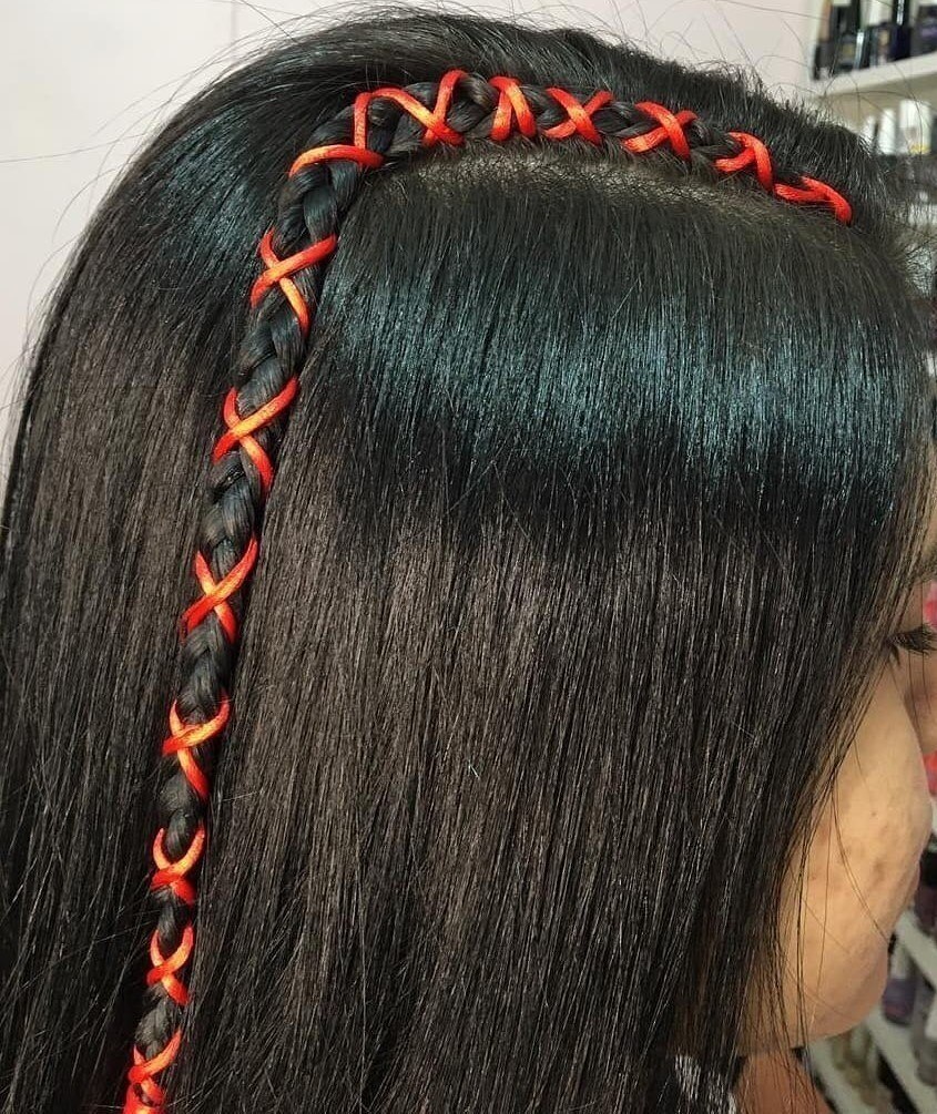 Mulher posa de perfil com trancinha com fita fio de seda vermelha