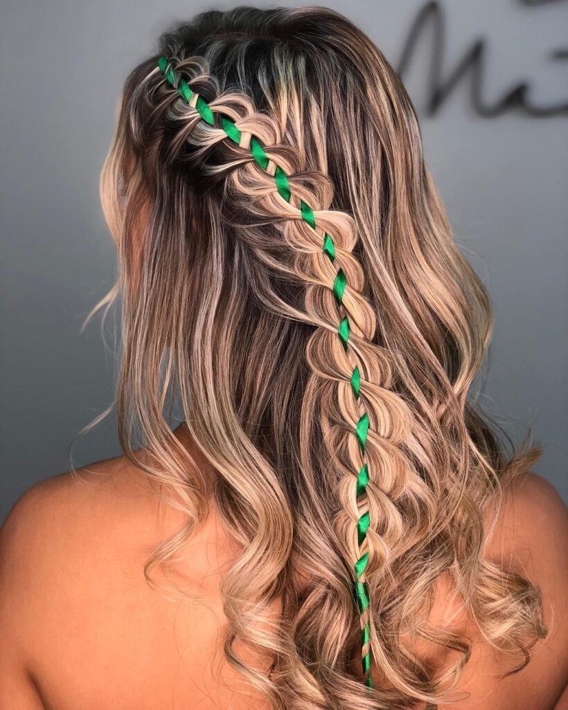 Mulher loira de trança de trança com fita verde de cetim no cabelo