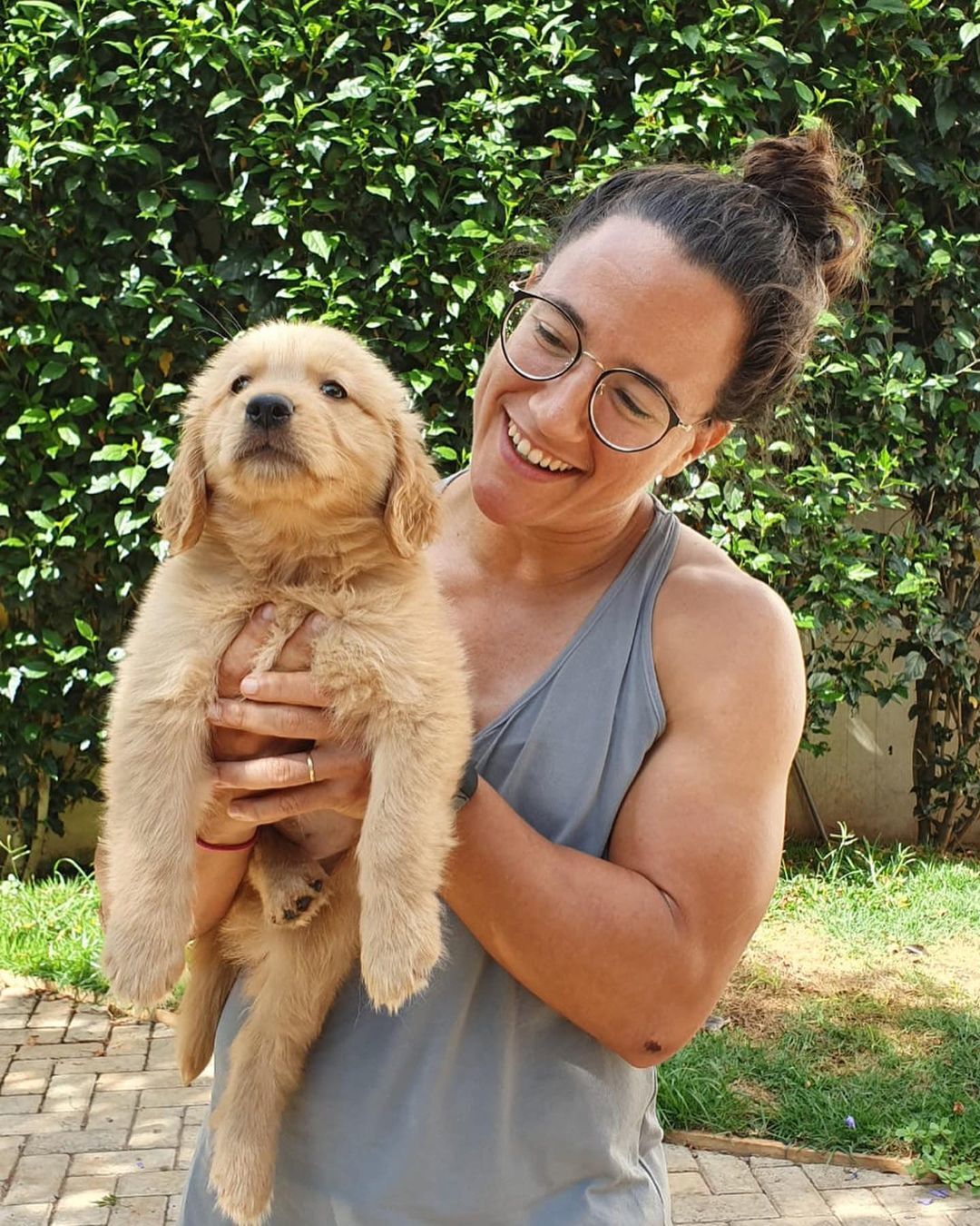Isadora Cerullo, jogadora de rugby, usa coque no cabelo e segura seu cachorro no colo