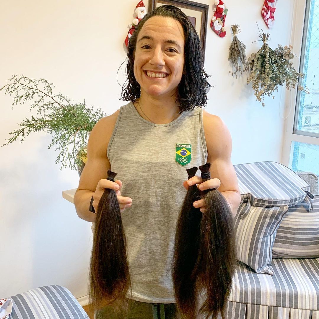 Isadora Cerullo, jogadora de rugby, segura as mechas de cabelo que cortou para doar