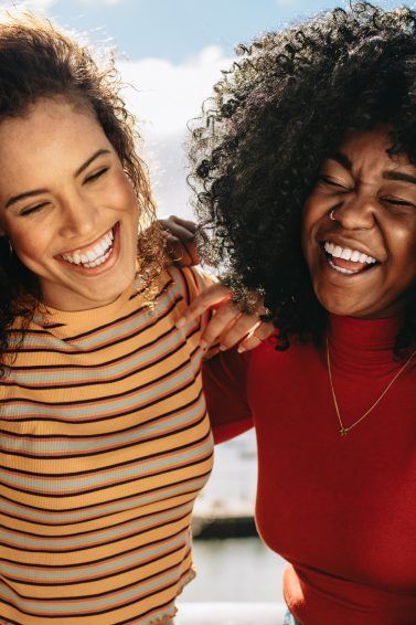 Duas amigas de cabelos cacheados se abraçam