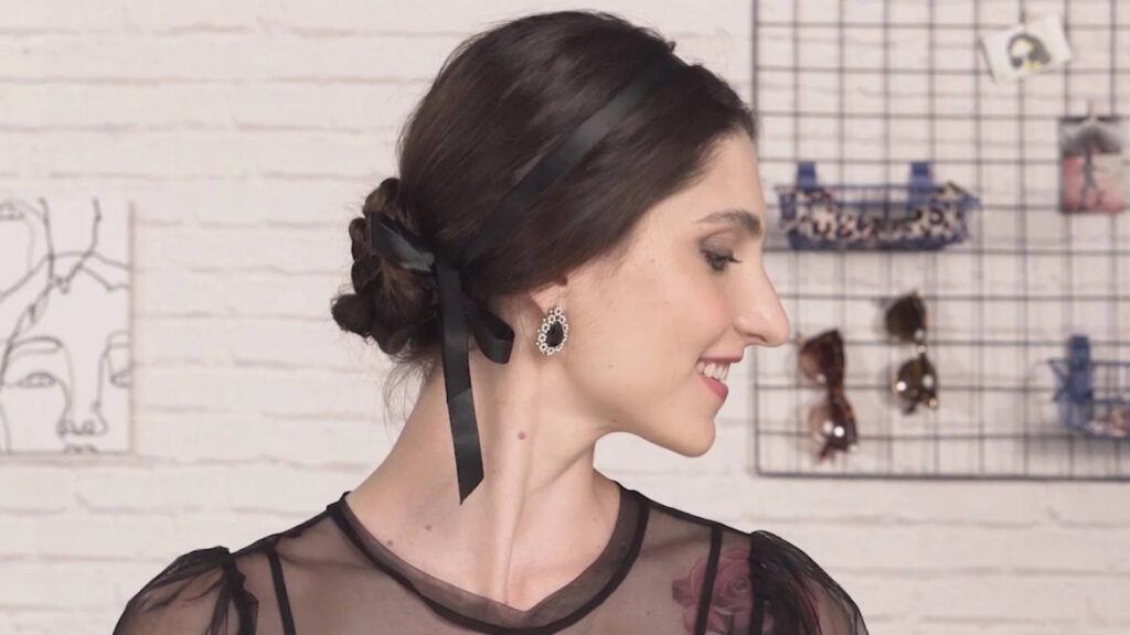 mulher de lado com coque com trança e fita