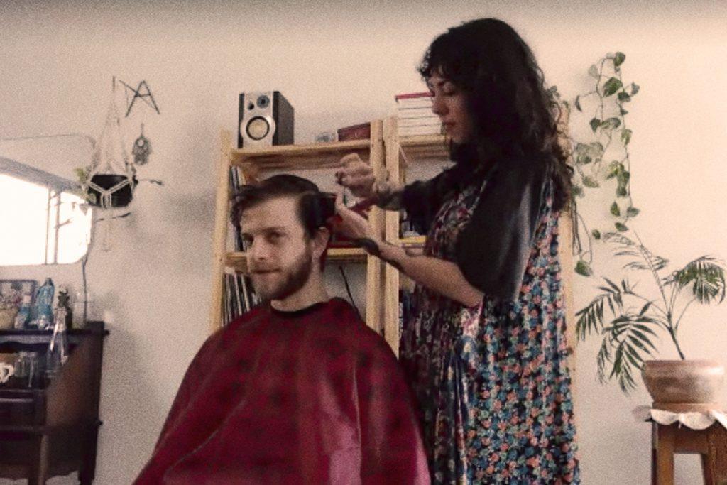 mulher de pé corta cabelo de homem sentado