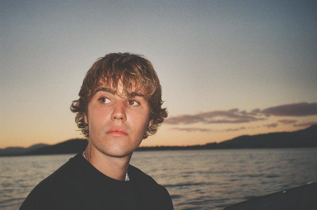 justin bieber com cabelo no rosto olhando para o lado
