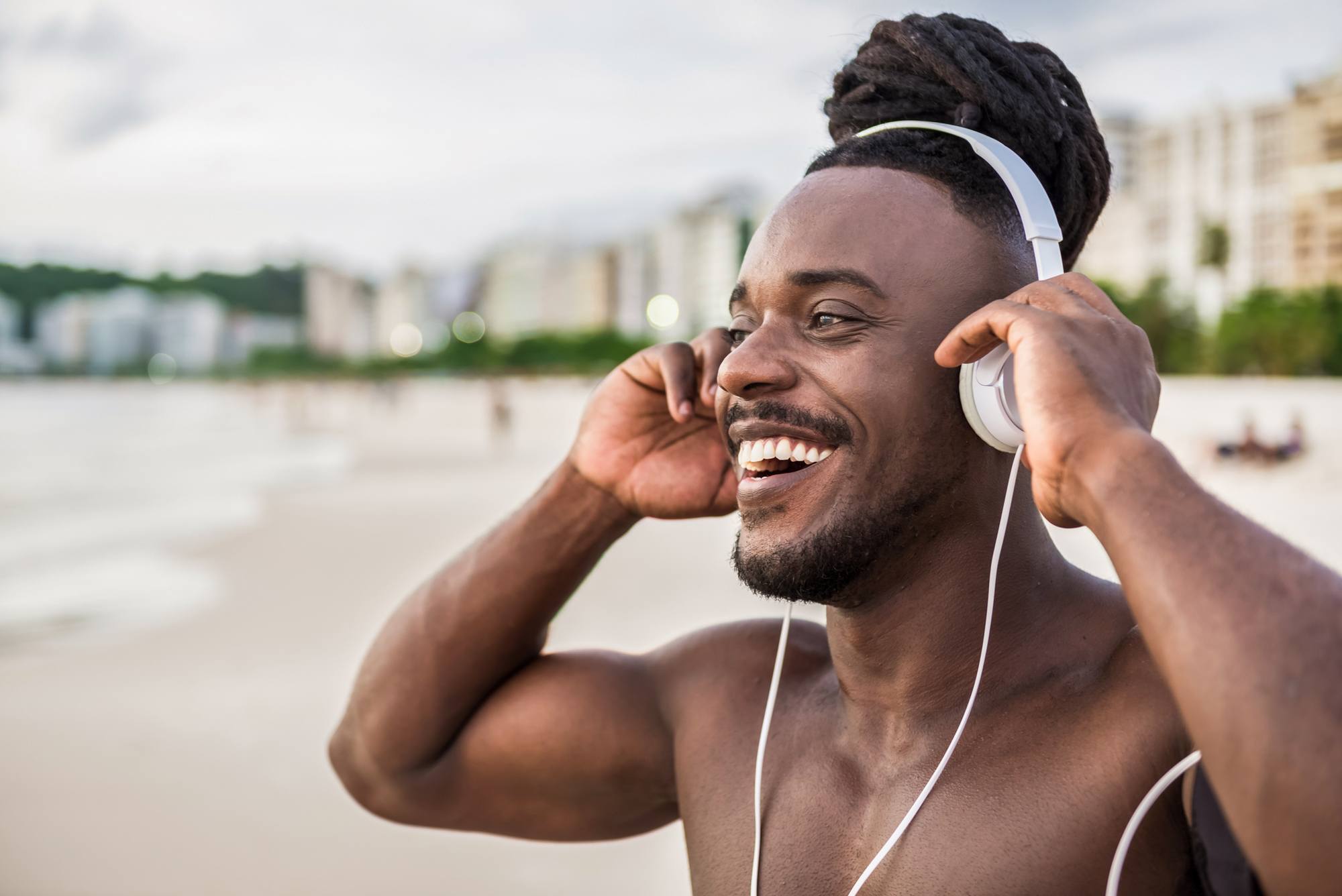 Homem com cabelo afro com fones de ouvido na praia