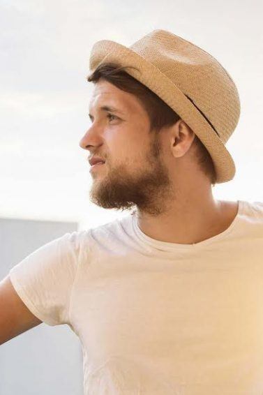 Homem com chapéu, cabelo curto e barba no verão
