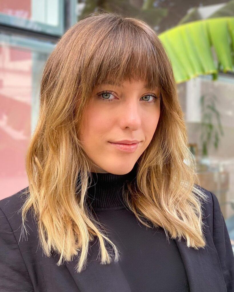 mulher com cabelo loiro longo e franja desfiada lisa curta
