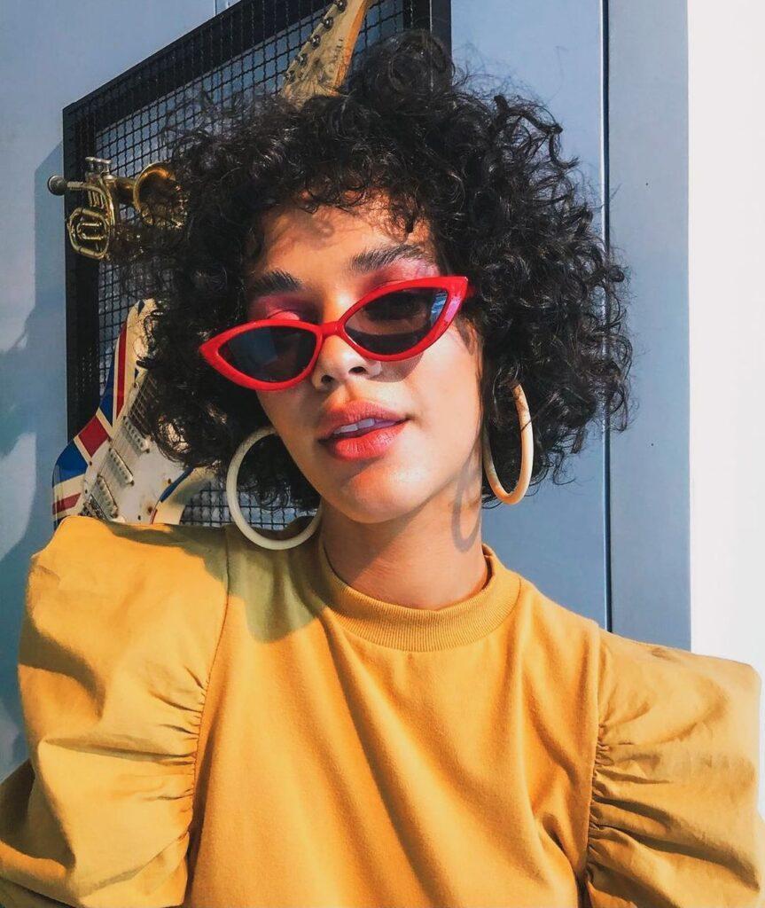 mulher com cabelo chanel cacheado e franja curta