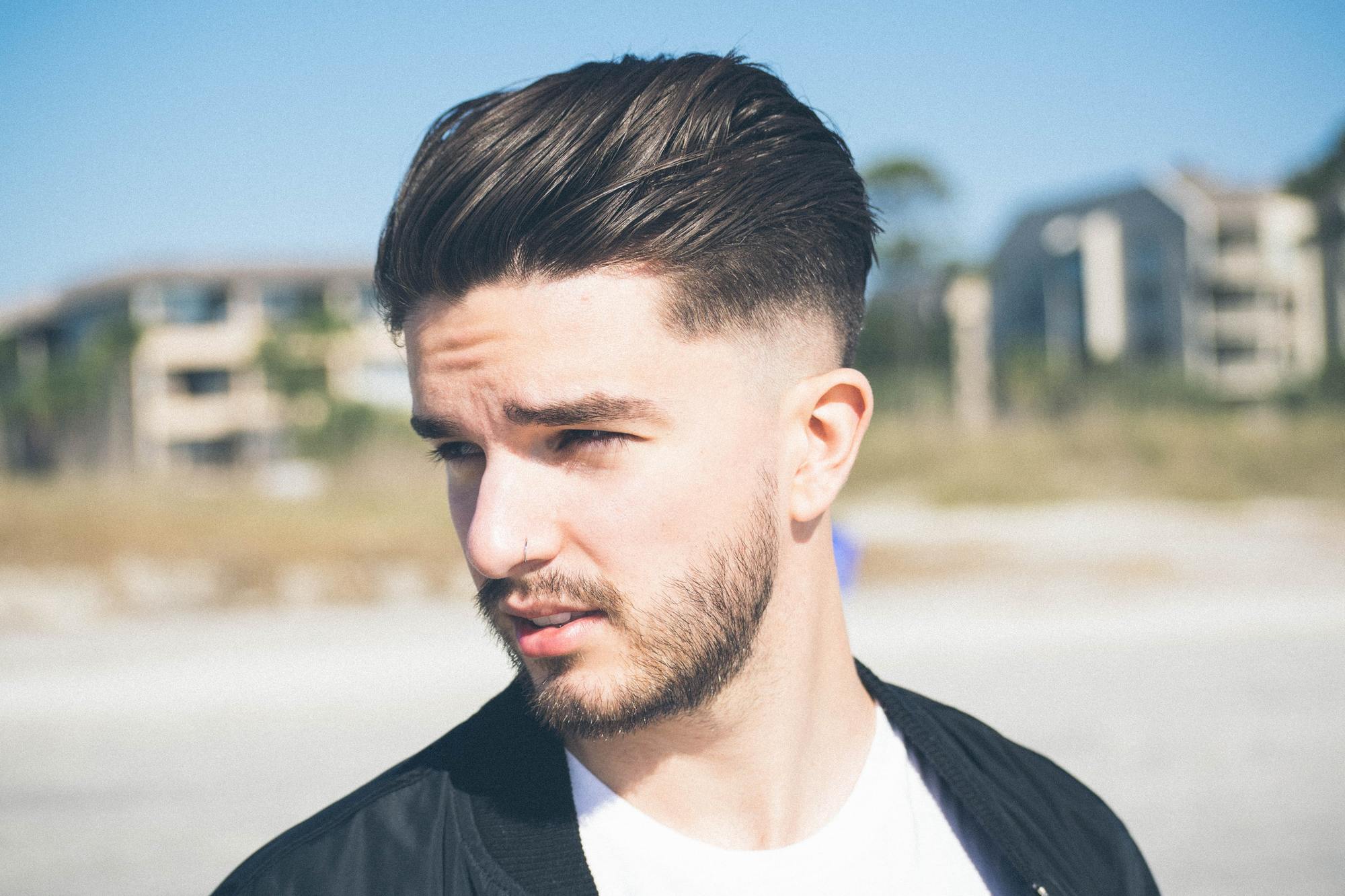 homem posa ao ar livre de perfil com corte de cabelo undercut
