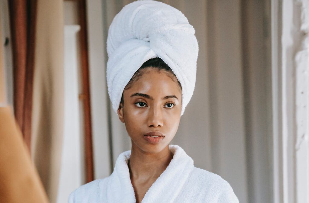 Mulher de cabelo cacheado posa de toalha na cabeça no pós-banho