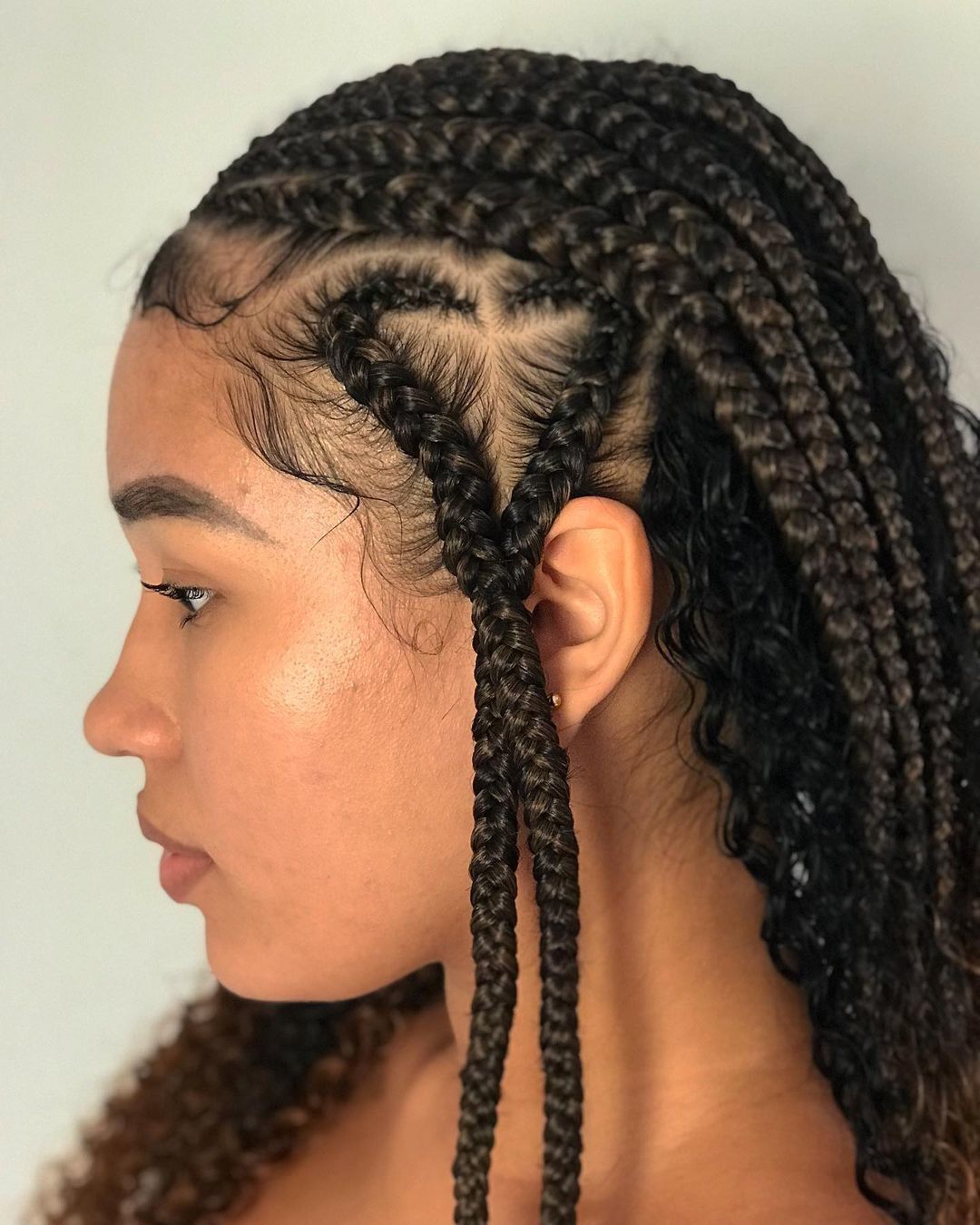 Mulher com tranças fulani posa de perfil destacando o formato de coração das tranças