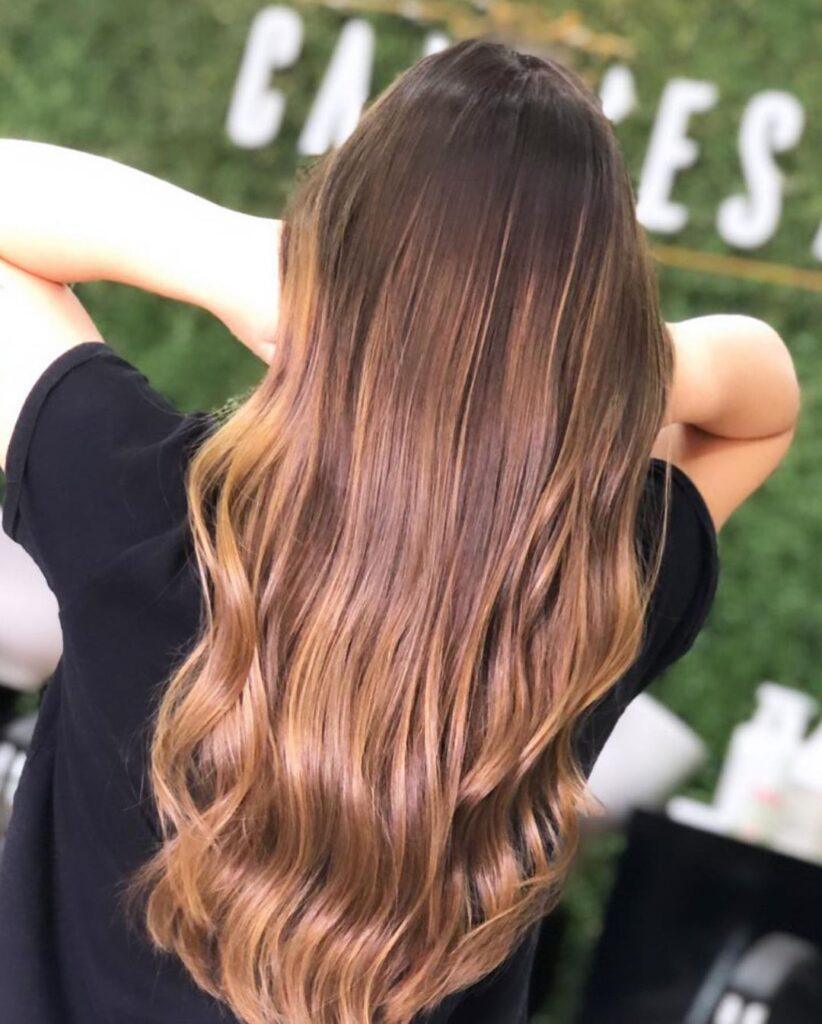 Mulher com reflexo no cabelo castanho avermelhado longo