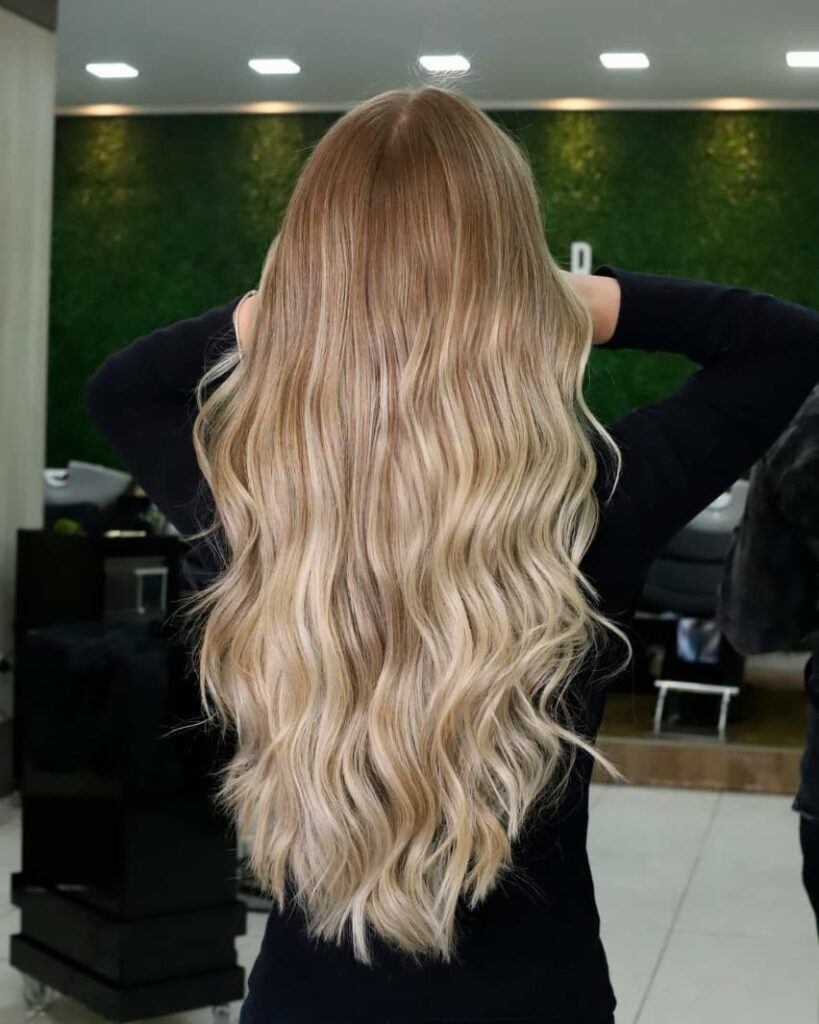 Mulher com reflexo no cabelo loiro, longo e liso