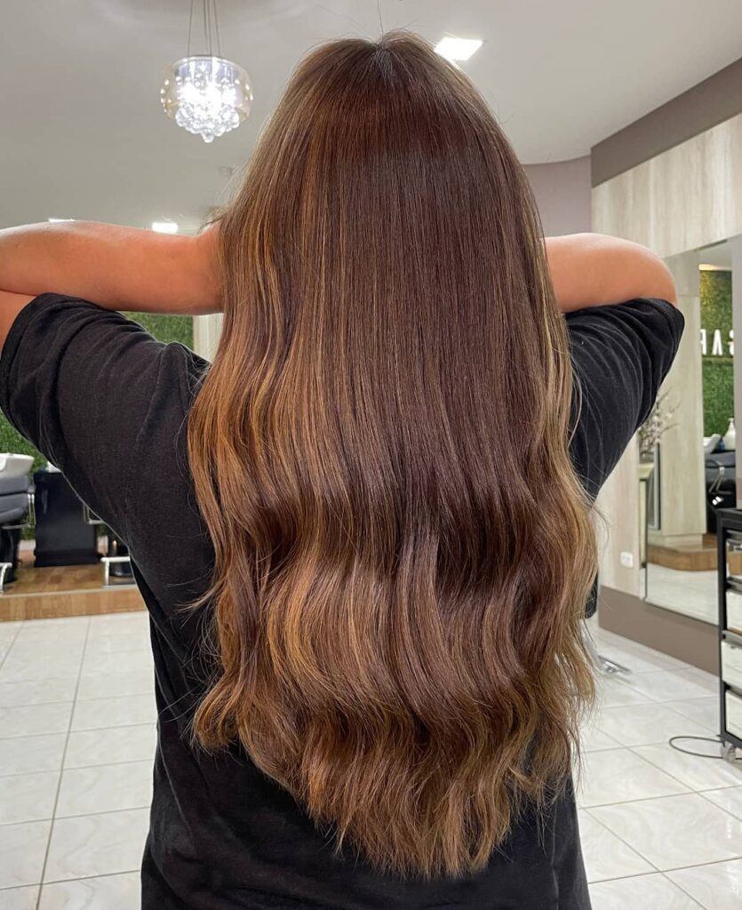 Mulher com reflexo no cabelo castanho avermelhado liso