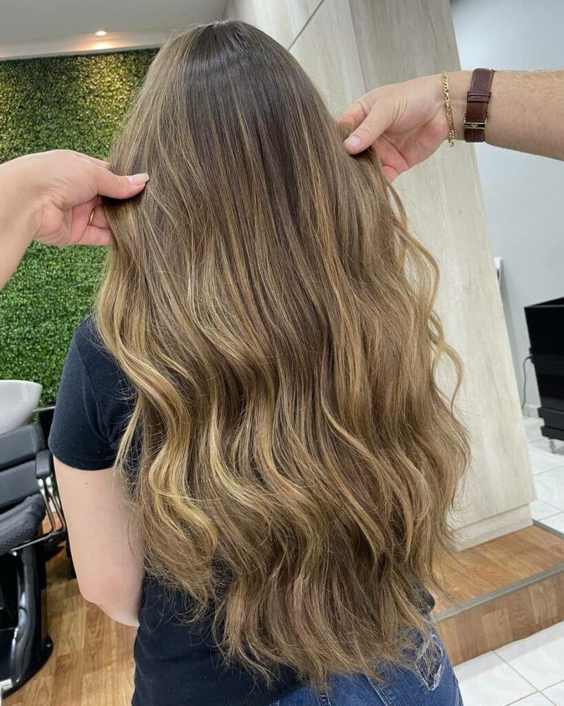 Mulher com reflexo no cabelo castanho claro longo e liso