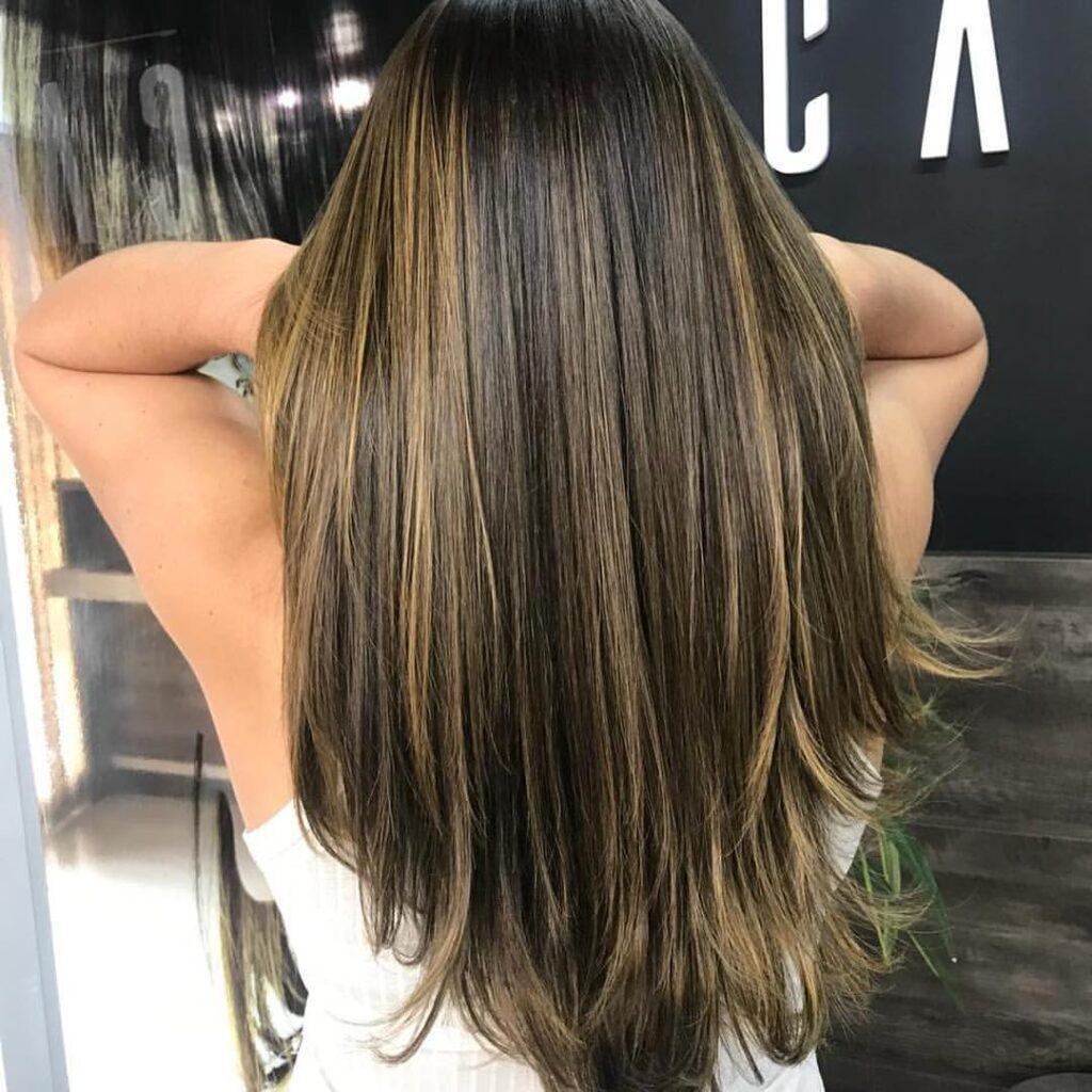 Mulher com reflexo no cabelo longo liso e castanho