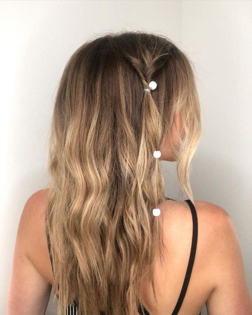 Mulher posa de costas com tererê branco estilo hair clip de plástico removível no cabelo loiro e ondulado