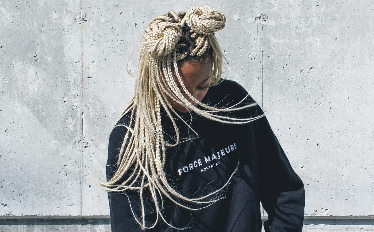 mulher posa de moletom com tranças finas boxer braids loiras descoloridas e dois coques altos
