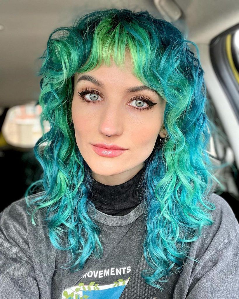 mulher com wolf cut em cabelo cacheado longo colorido