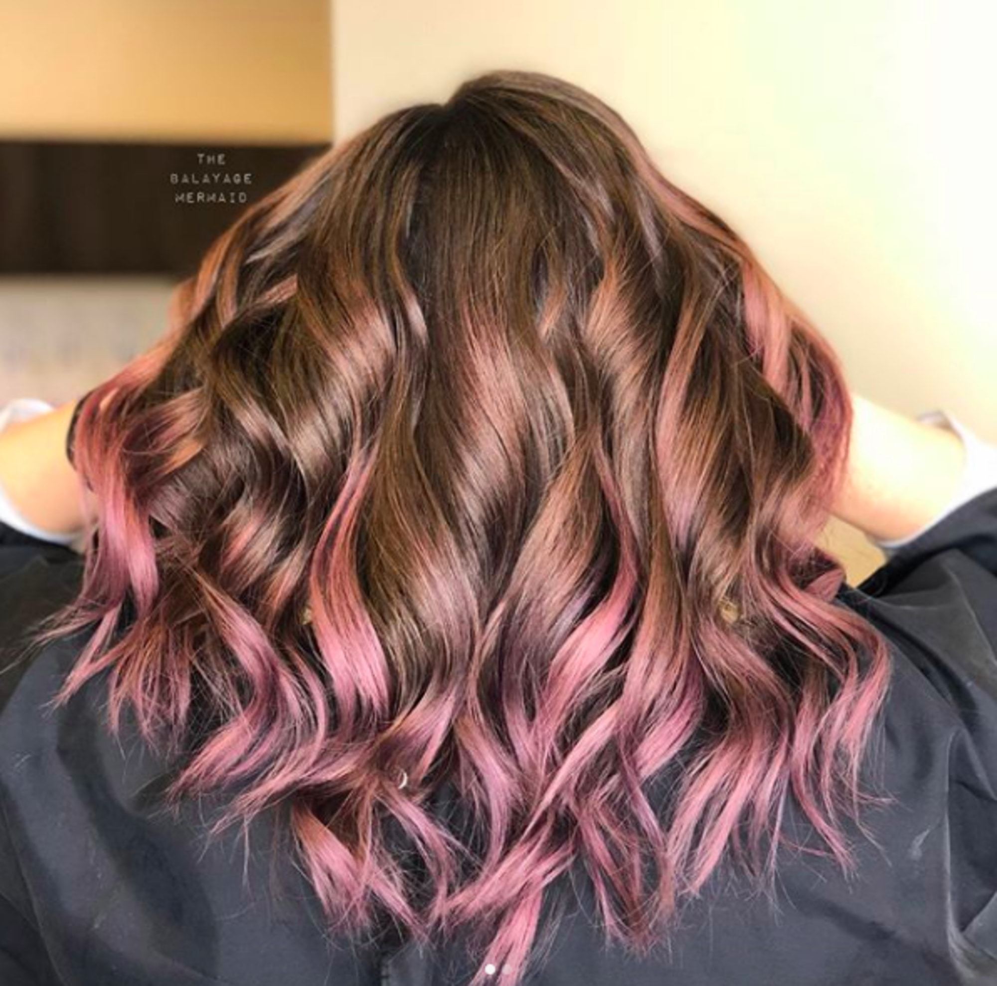 Mulher com cabelos cacheados e mechas lilás