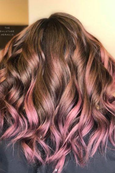 Mulher com cabelos cacheados e mechas lilás