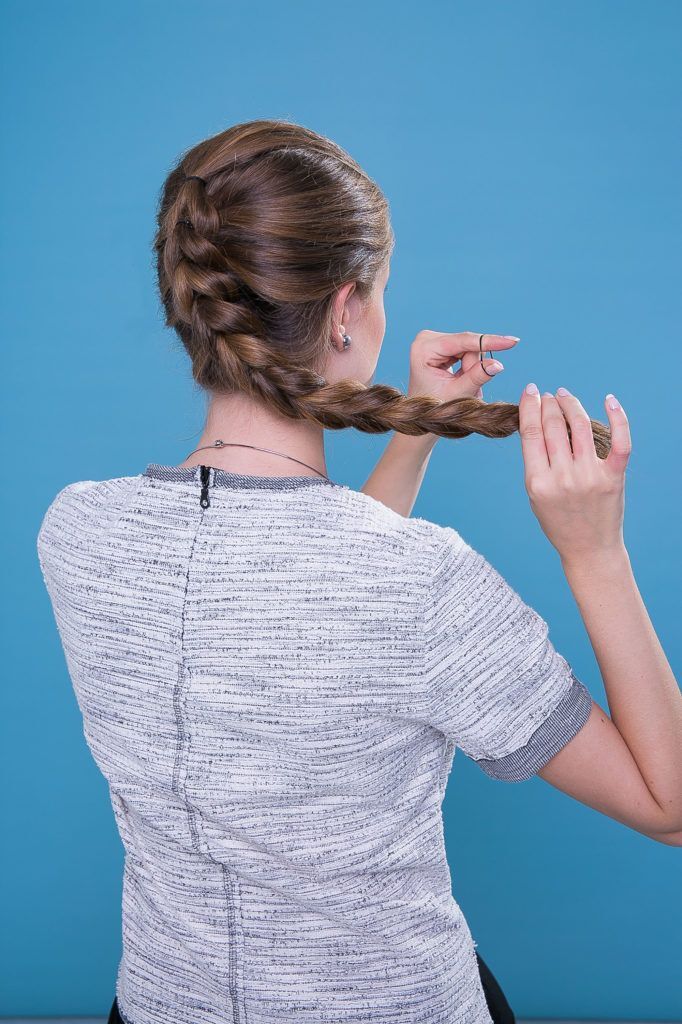 Mulher com cabelos castanho-claro fazendo trança escama de peixe