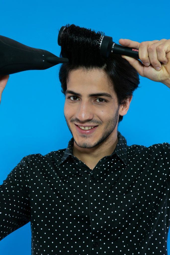 modelo masculino escovando os fios com escova e secador