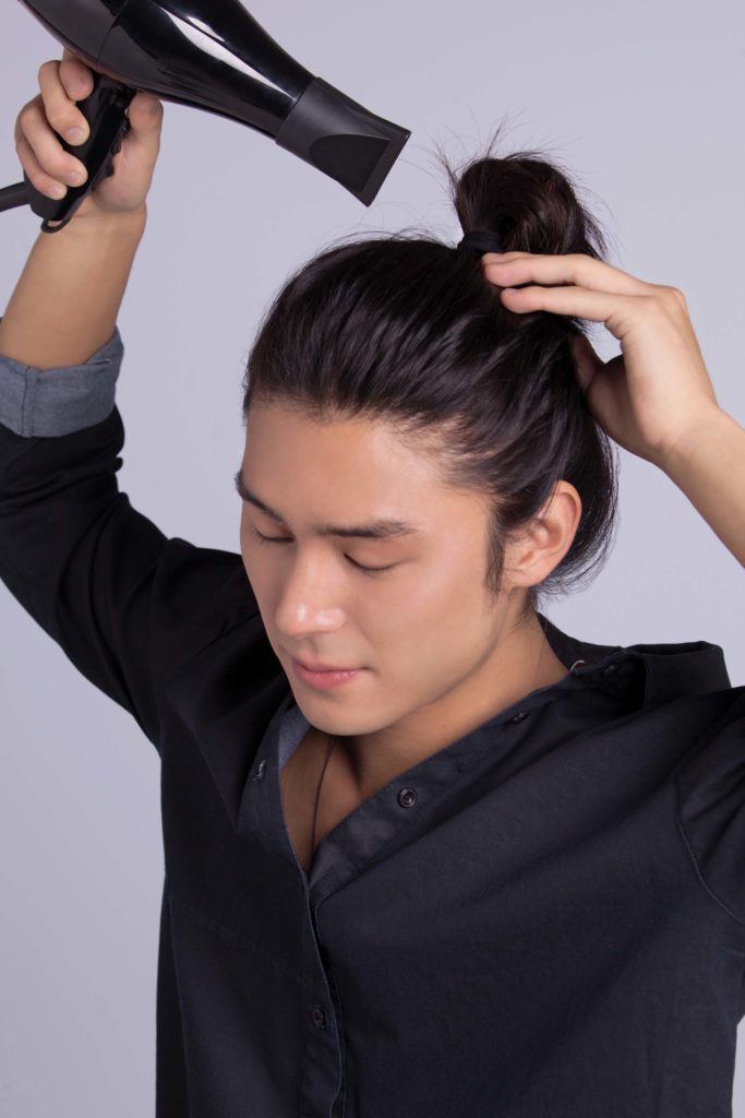 Modelo faz o penúltimo passo de como fazer cabelo masculino com ondas: