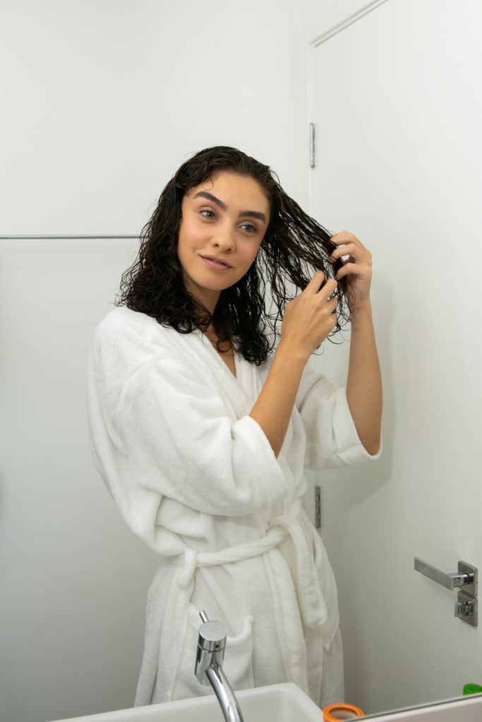modelo massageia os cabelos cacheados molhados.
