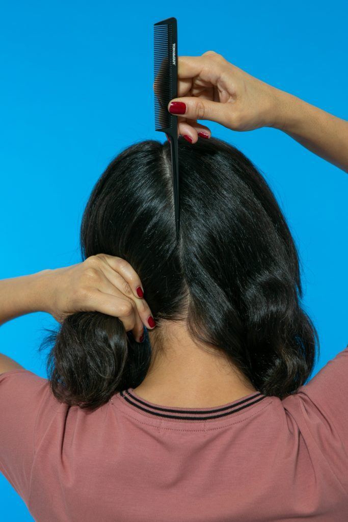 modelo de costas partindo o cabelo no meio com um pente fino
