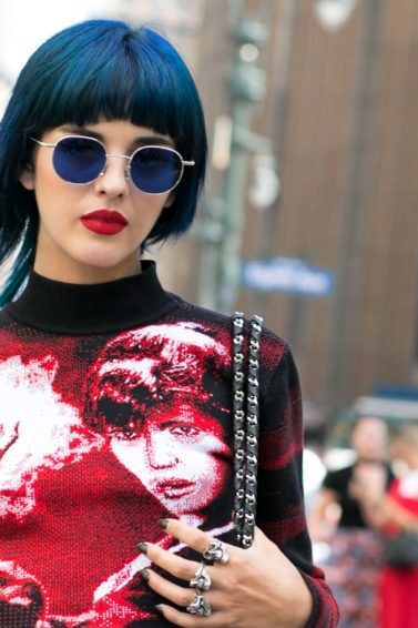 Mulher usa franja curtinha, óculos escuros redondos e batom vermelho, em NYC