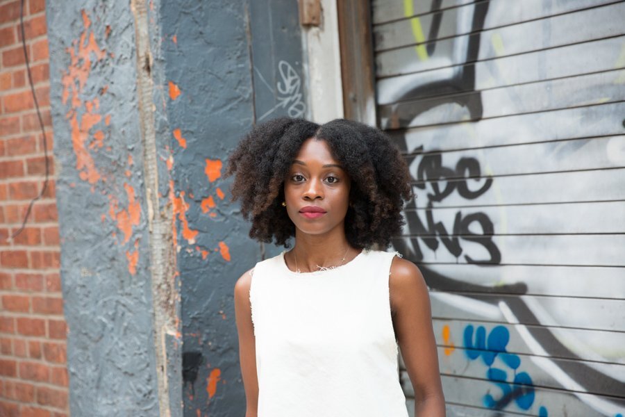 Mulher usa cabelo partido ao meio, e veste vestido branc